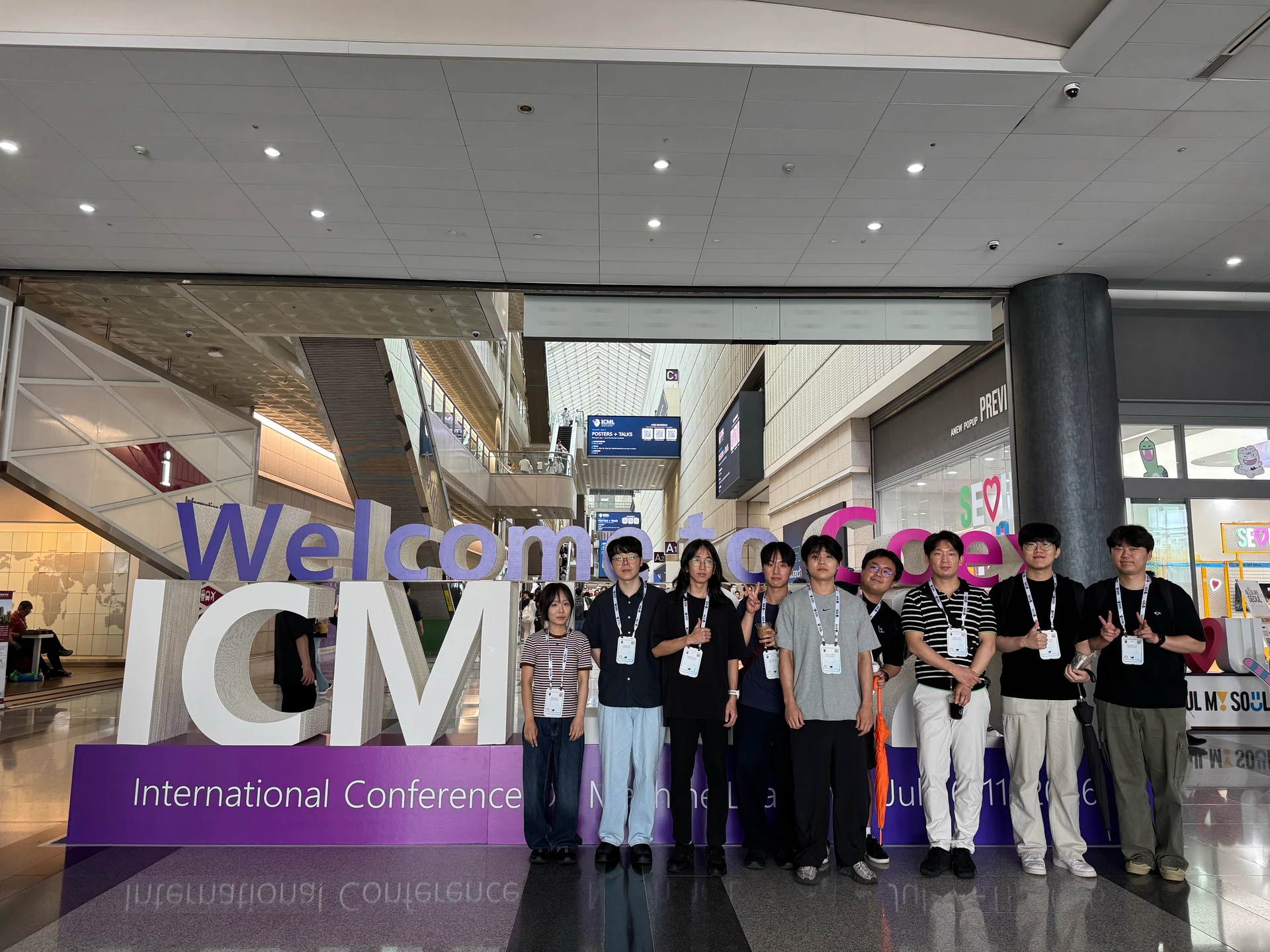 Lab members together in front of the ICML conference sign at ICML 2026.